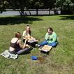 3 Mädchen sitzen auf der Wiese und essen Pizza