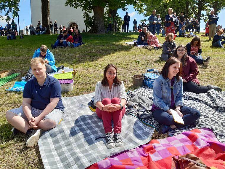 junge Gottesdienstbesucher*innen sitzen auf Decken