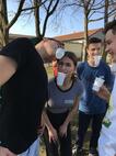 Jugendliche gibt Wasser mit einem Becher im Mund weiter an zweite Person